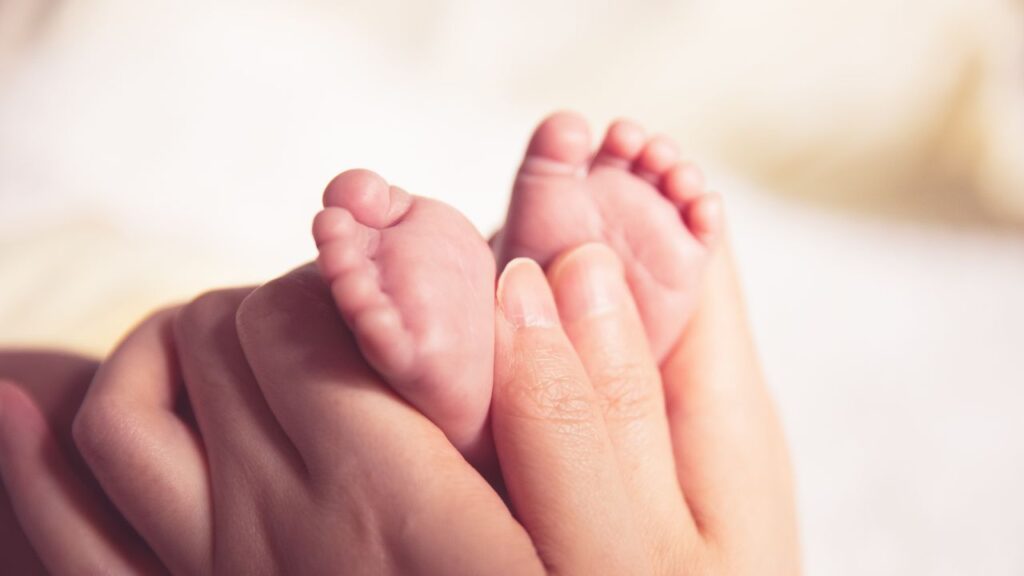 Hand hält Babyfüße